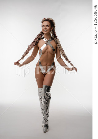 Woman in silver body art poses confidently in lingerie-inspired outfit Woman in silver body art poses confidently in lingerie-inspired outfit 125658646