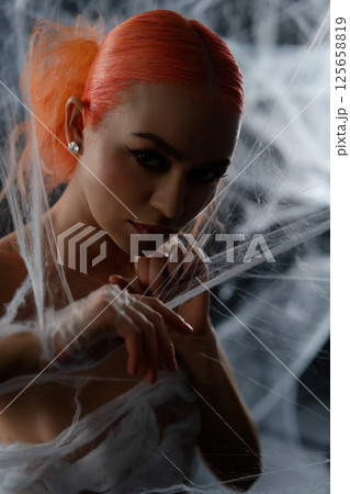 Red-haired woman entangled in a delicate web during a mysterious night 125658819