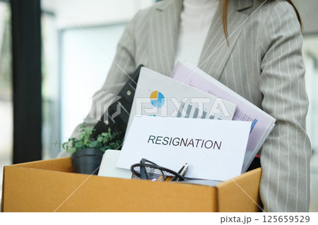 Resignation concept. Businesswoman packing personal belongings deciding resignation change of job or fired from the company. Resignation concept. Businesswoman packing personal belongings deciding resignation change of job or fired from the company. 125659529