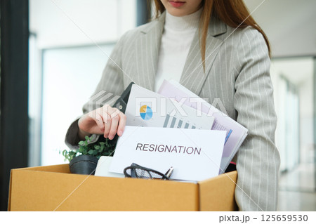 Resignation concept. Businesswoman packing personal belongings deciding resignation change of job or fired from the company. Resignation concept. Businesswoman packing personal belongings deciding resignation change of job or fired from the company. 125659530