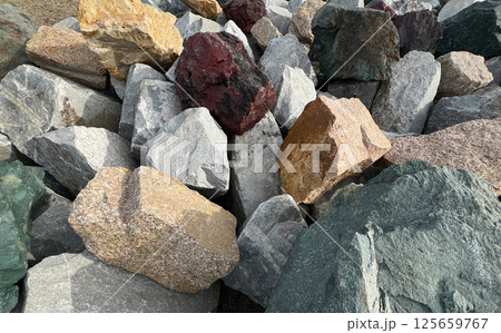 Assortment of variously colored rocks closely arranged outdoors, natural textures and hues - grey, brown, red, and green stones for geological observation Assortment of variously colored rocks closely arranged outdoors, natural textures and hues - grey, brown, red, and green stones for geological observation 125659767