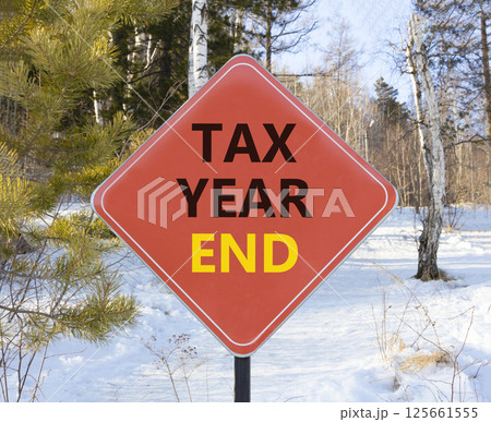 Tax year end symbol. Concept words Tax year end on beautiful red road sign. Beautiful snow forest background. Business tax year end concept. Copy space. 125661555