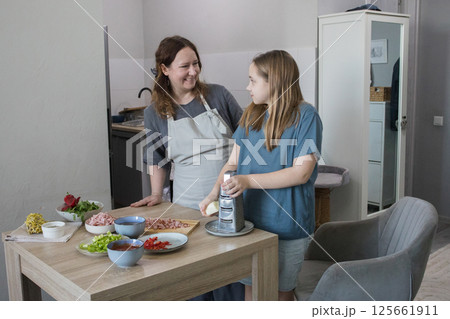 Mother and child daughter girl are cooking and having fun in the kitchen.  125661911