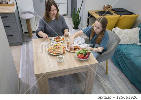 Top view of woman and child girl eating homemade pizza. Mother and daughter resting at home Top view of woman and child girl eating homemade pizza. Mother and daughter resting at home 125661926