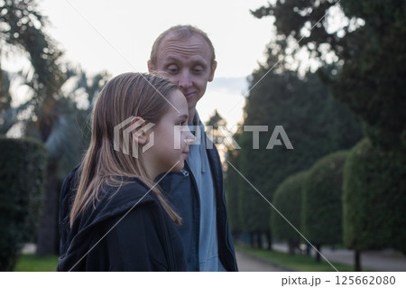 Family outdoors portrait. Young daughter child girl and her father walking outdoors.  125662080