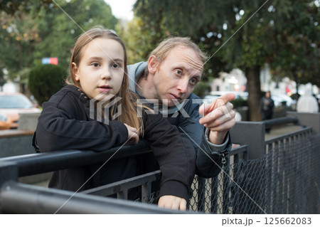Curious daughter child girl and her father together looking at nature and pointing. Happy family Curious daughter child girl and her father together looking at nature and pointing. Happy family 125662083