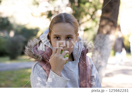 Portrait of young girl with apple fruit in park. Child 10 years old 125662281