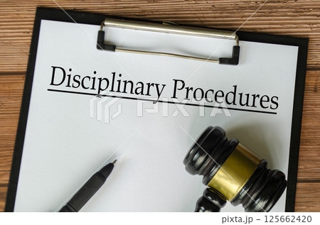 Top view of Disciplinary Procedures text on white paper clipboard with gavel. Compliance concept 125662420