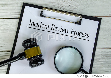 Top view of Incident Review Process text on white paper clipboard with gavel and magnifying glass Top view of Incident Review Process text on white paper clipboard with gavel and magnifying glass 125662427