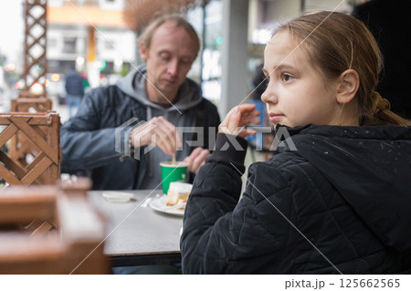 Young daugther and her father drinking coffee together in cafe 125662565