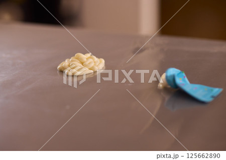 A closeup view of a sticky substance resting on a surface while being handled with a tool A closeup view of a sticky substance resting on a surface while being handled with a tool 125662890