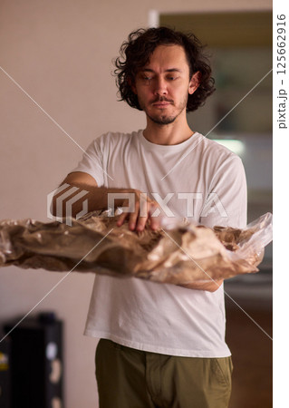A Man Unpacking Materials in a Modern, Stylish, and Organized Kitchen Environment 125662916