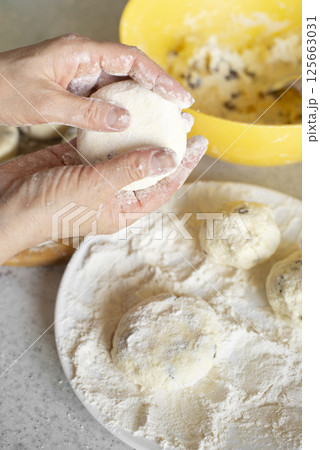 Caucasian hands making cottage cheese pancakes with raisins Caucasian hands making cottage cheese pancakes with raisins 125663031