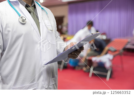 Doctor in gown uniform with stethoscope standing and holding chart in the quarantine room for the corona virus infected patients. Doctor in gown uniform with stethoscope standing and holding chart in the quarantine room for the corona virus infected patients. 125663352