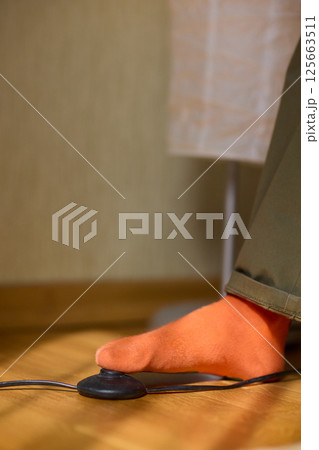 A foot is on a footswitch in a cozy, stylish indoor setting that feels welcoming 125663511