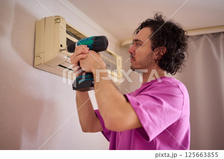 Technician Expertly Installing a New Air Conditioning Unit in a Contemporary Modern Home 125663855