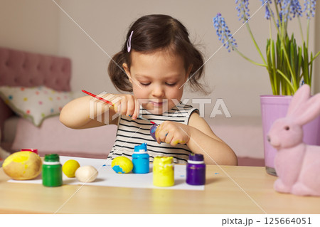 Little child girl paint Easter eggs at home. kid is preparing for Easter. Little child girl paint Easter eggs at home. kid is preparing for Easter. 125664051