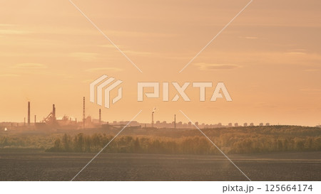 An Industrial Landscape at Dusk Featuring Smokestacks and Notable Pollution Effects Present 125664174