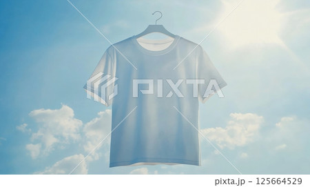 White t-shirt on hanger floating against bright sky, minimalistic fashion concept 125664529