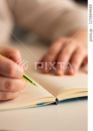 Side view of hand writing notes with pen in plain notebook. Minimalist workspace with natural lighting. 125664689