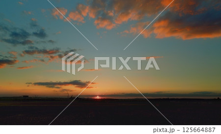 A Stunning Sunset Over a Calm Horizon Accompanied by Colorful and Dramatic Clouds A Stunning Sunset Over a Calm Horizon Accompanied by Colorful and Dramatic Clouds 125664887