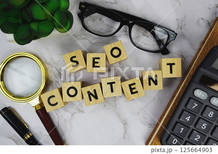 SEO Content with wooden blocks alphabet letters and Magnifying glass and calculator on marble background 125664903