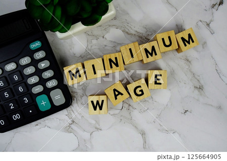 Minimum Wage with wooden blocks alphabet letters and Calculator on marble background Minimum Wage with wooden blocks alphabet letters and Calculator on marble background 125664905
