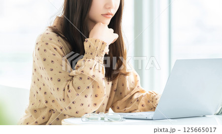 パソコンの画面を見ながら考える女性・ビジネスウーマン 125665017