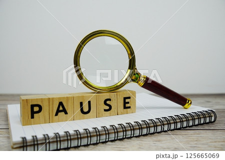 Magnifying glass with wooden blocks alphabet letters PAUSE on paper notebook text message on wooden background Magnifying glass with wooden blocks alphabet letters PAUSE on paper notebook text message on wooden background 125665069