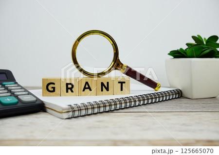 Magnifying glass and calculator with wooden blocks alphabet letters GRANT text message on wooden background Magnifying glass and calculator with wooden blocks alphabet letters GRANT text message on wooden background 125665070