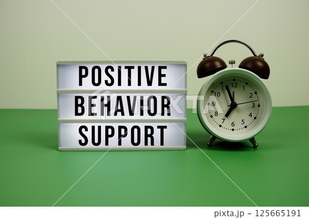 Positive Behavior Support text on light box with alarm clock on green background Positive Behavior Support text on light box with alarm clock on green background 125665191