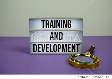 Training and Development text on LED lightbox with magnifying glass on purple background Training and Development text on LED lightbox with magnifying glass on purple background 125665212
