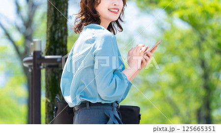 屋外でスマートフォンを使う笑顔の女性・ビジネスウーマン 125665351