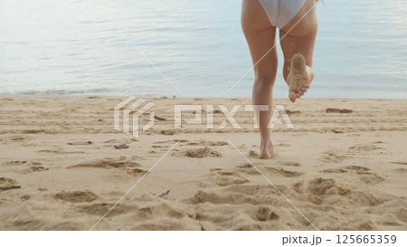Back view, Young beautiful woman wearing bikini swimsuit running into tropical on sand beach to water, Happy Asian female have fun she run holiday outside, Summer travel vacation concept Back view, Young beautiful woman wearing bikini swimsuit running into tropical on sand beach to water, Happy Asian female have fun she run holiday outside, Summer travel vacation concept 125665359