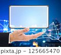 Business Hand Holding Holographic Tablet in Cityscape copy space 125665470