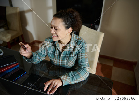 Woman Smiling While Using Laptop for Online Shopping at Home Workspace 125665566