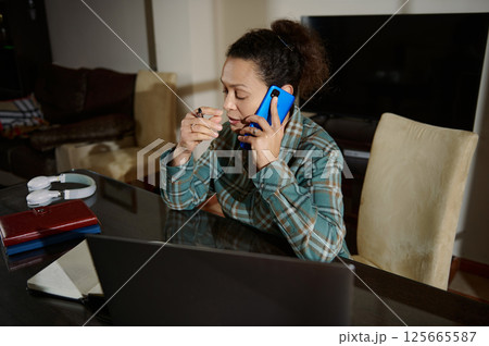 Woman Working From Home Office on Phone and Planning on Laptop 125665587
