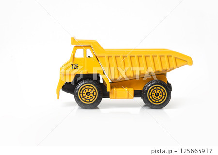 A yellow toy dump truck with detailed wheels and a simplistic design on white background A yellow toy dump truck with detailed wheels and a simplistic design on white background 125665917