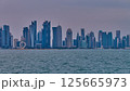 Doha Qatar skyline from corniche promenade sunset shot showing dhows in Arabic gulf with Qatar flag 125665973