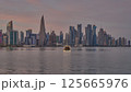 Doha Qatar skyline from corniche promenade sunset shot showing dhows in Arabic gulf with Qatar flag 125665976