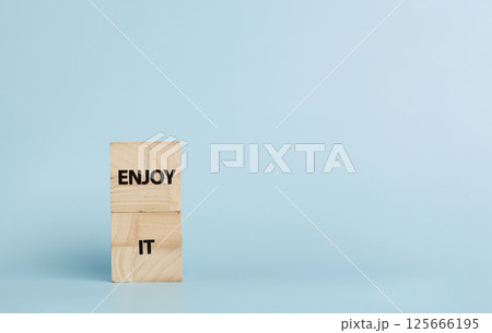 Wooden cubes with inscriptions Enjoy It on a blue background Wooden cubes with inscriptions Enjoy It on a blue background 125666195