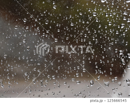 Raindrops cascading down glass surface, forming delicate, translucent streams during wet weather condition Raindrops cascading down glass surface, forming delicate, translucent streams during wet weather condition 125666545