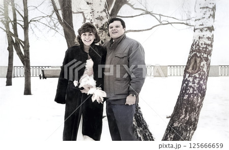 Vintage portrait of a bride and groom on the bank of a snowy river. Retro photo from 1993. 125666659