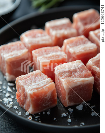 Fresh raw pork cubes with salt on black plate - perfect for gourmet cooking and delicious meals Fresh raw pork cubes with salt on black plate - perfect for gourmet cooking and delicious meals 125668741