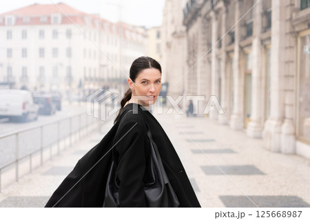 Businesswoman in black coat standing on sidewalk 125668987