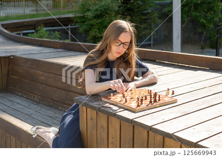 Caucasian woman playing chess outdoors. Caucasian woman playing chess outdoors. 125669943