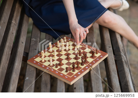 Caucasian woman playing chess outdoors. Caucasian woman playing chess outdoors. 125669958