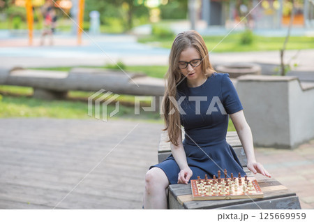 Caucasian woman playing chess outdoors. 125669959