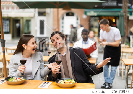 Girl in cafe sits near male companion, has nice conversation and discusses news of day 125670978