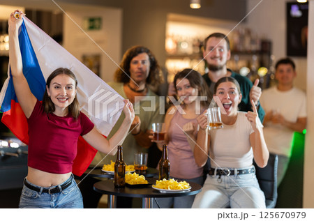 Men and women supporting Czech sports team in pub together. Group of friends raising Czech flag 125670979